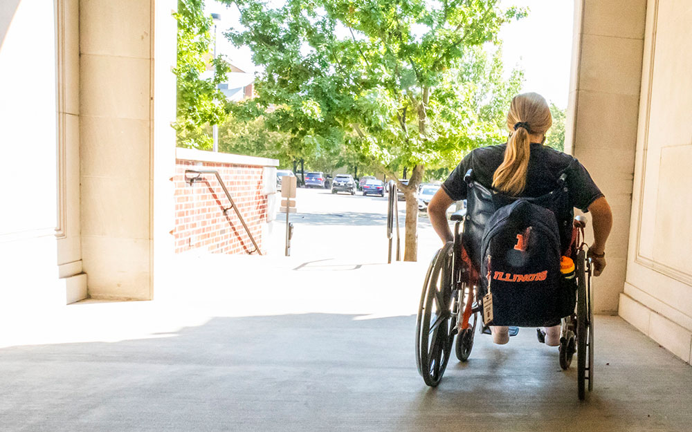 woman in wheelchair at back entrance of Huff Hall