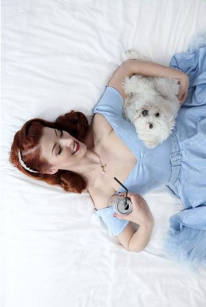 young girl in blue dress holding small white dog