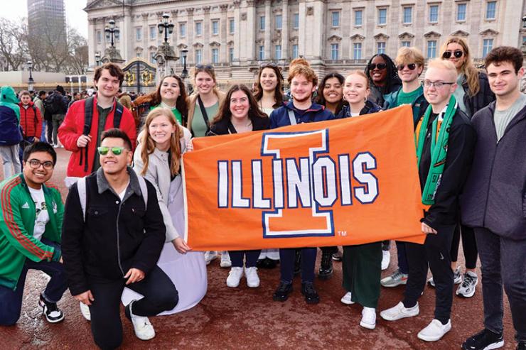 Image of a group of AHS students posing for a photo with a University of Illinois flag in London