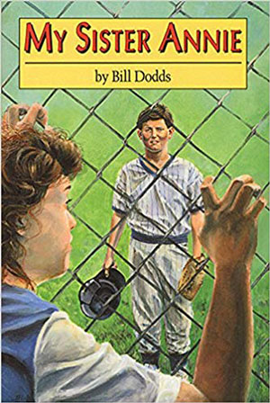 small girl looking through a chain link fence at a little league baseball player