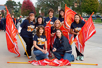 8 middle-aged women posing with bright orange flags