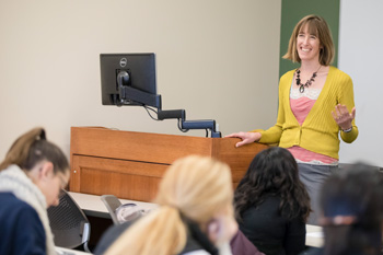 laughing teacher standing at podium in a classroom with students
